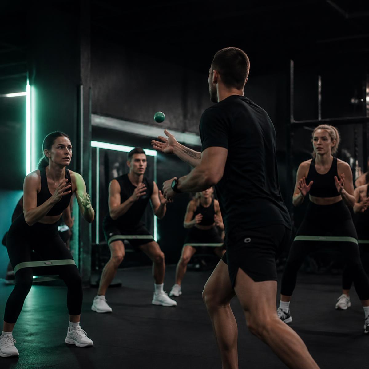 A trainer leads a smove group session in a dark gym with mint lighting